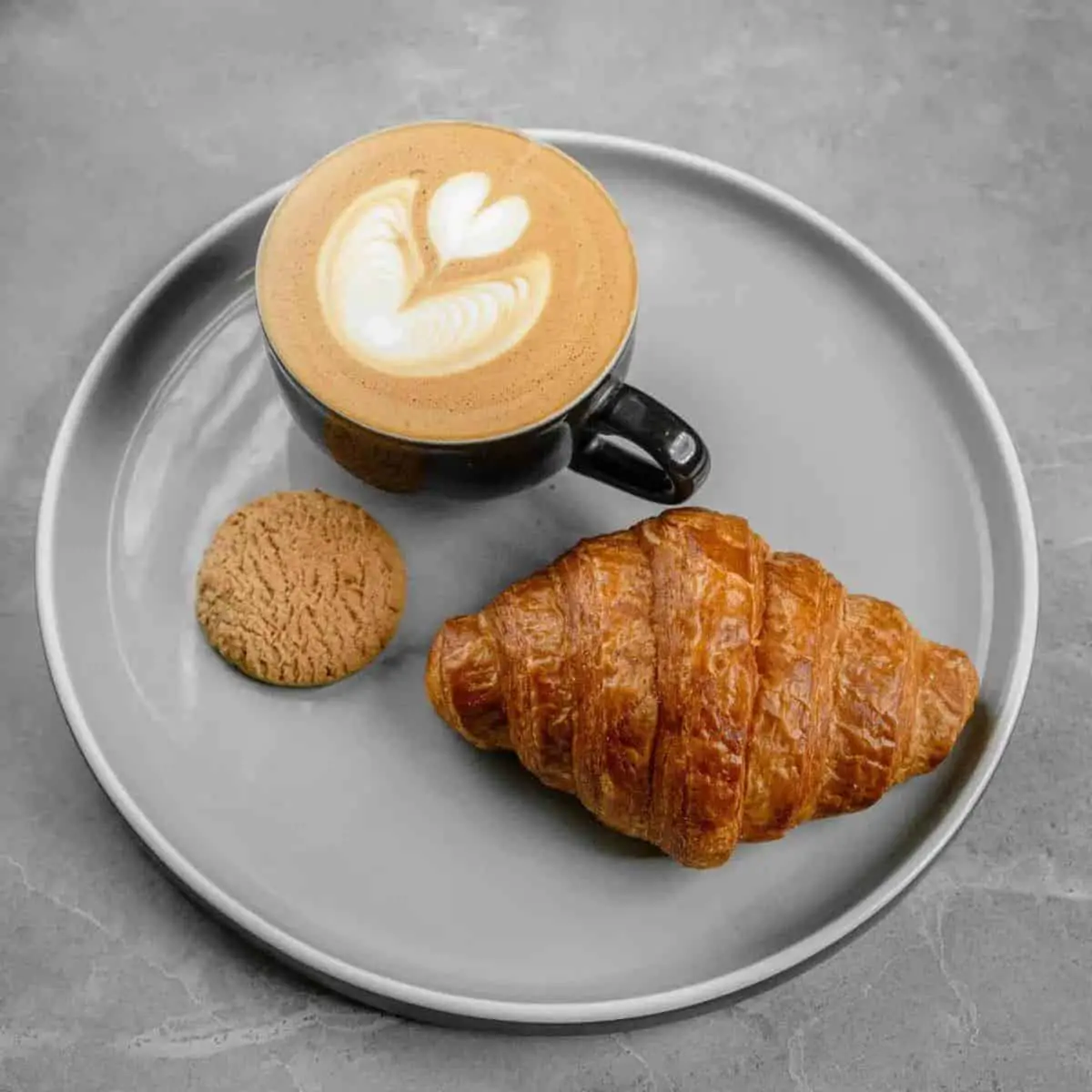 20 ml Coffee Hot latte and a butter croissant served on a gray plate
