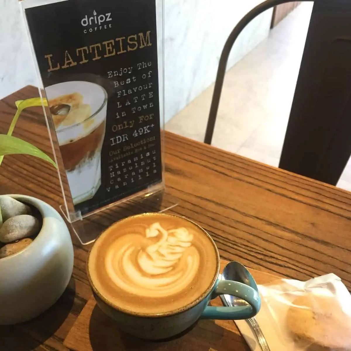 Dripz Coffee latte with art on top and a small plant on the side