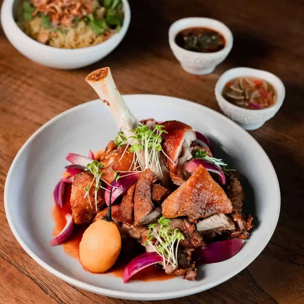 A full serving of crispy pork hock with tamarillo and small plates of side dishes from Mamasan