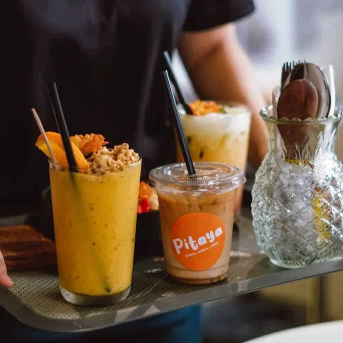 A waiter in Pitaya serving a tray of delectable beverages in transparent glasses