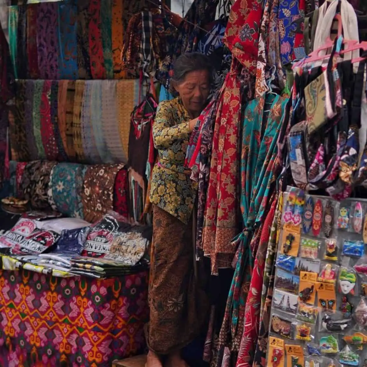 Old woman arranging the patterned sarongs in Ubud Market