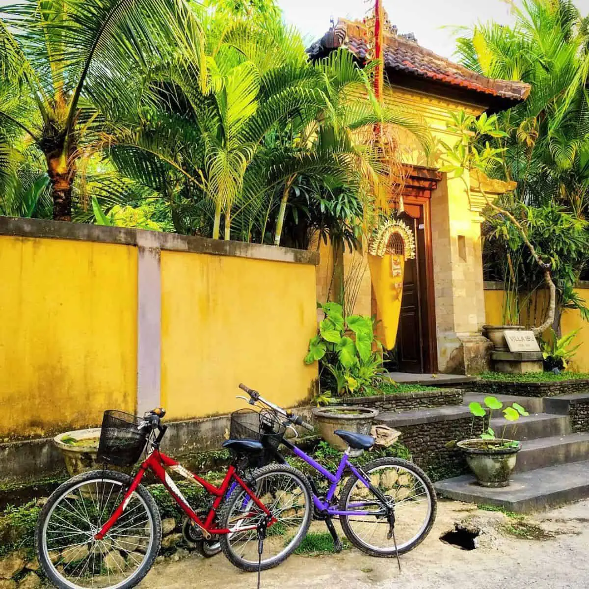 Two bicycles in red and purple in front of an entrance gate