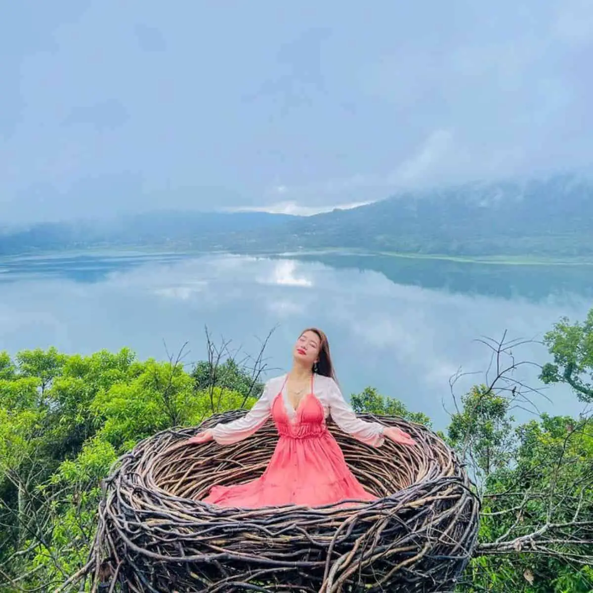 Very dramatic view of a lake in Wanagiri Hidden Hills with a woman sitting in a bird nest inhaling the fresh air
