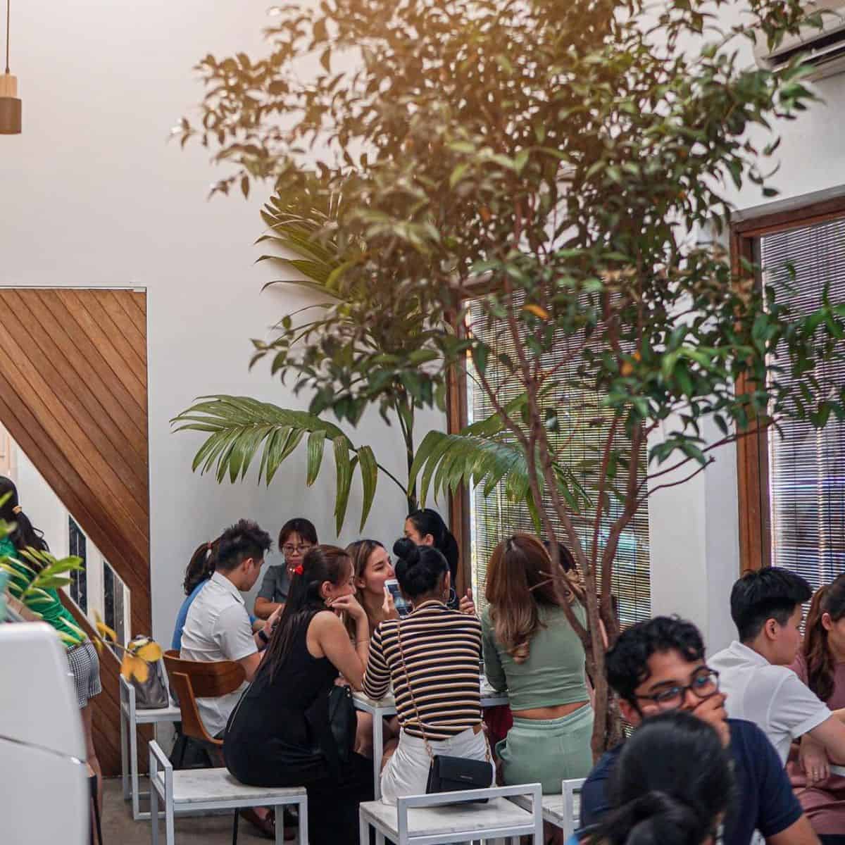 White and woody-themed interior of Norm Micro Roastery with many diners sitting around the tables