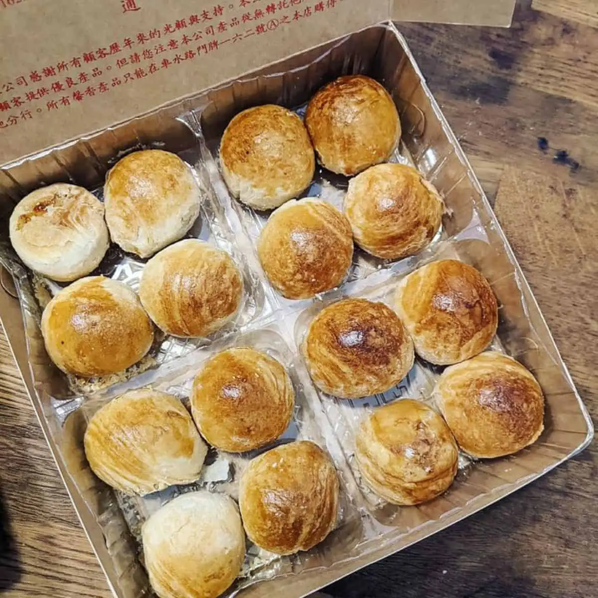 A brown box from Him Heang filled with mung bean pastry placed in a woody table