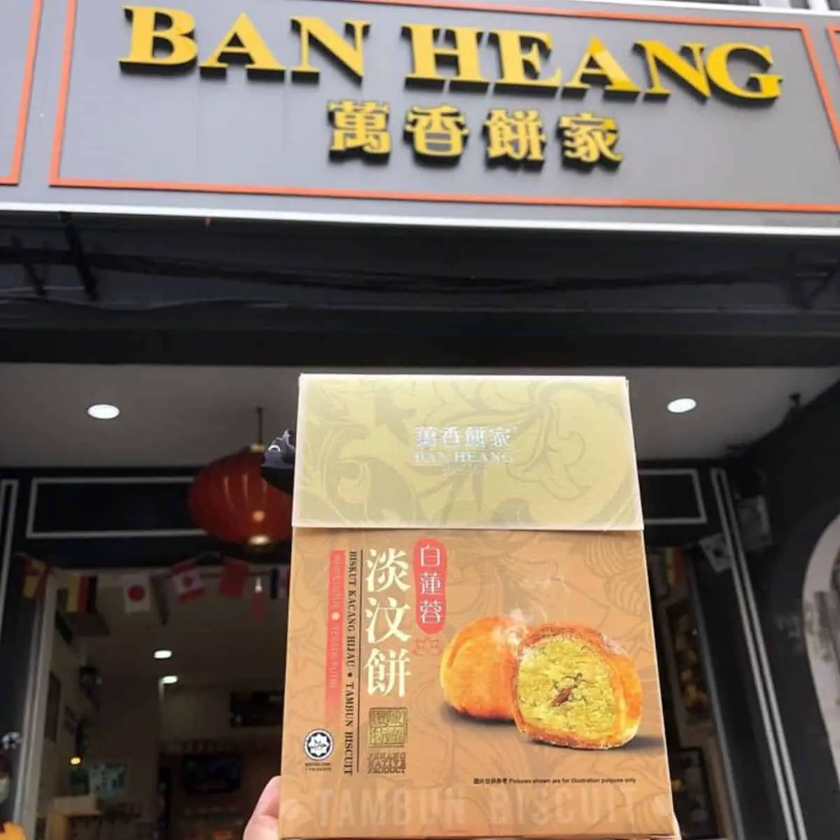 A person holding a box of tambun biscuits in front of Ban Heang building