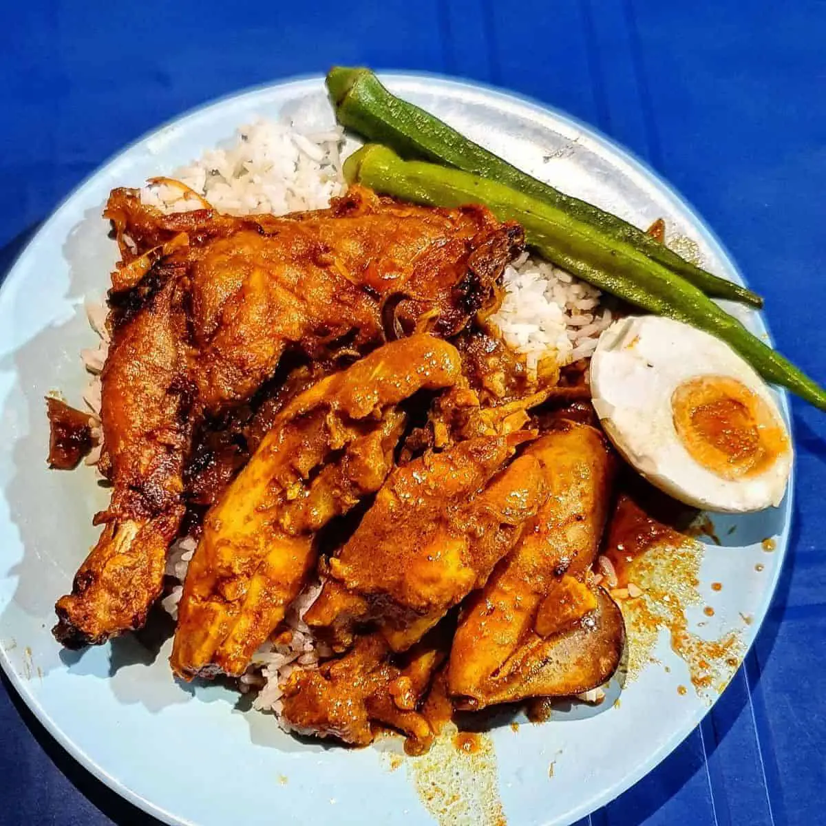 Beratur Original’s generous serving of chicken on top of a curry rice placed in a blue table