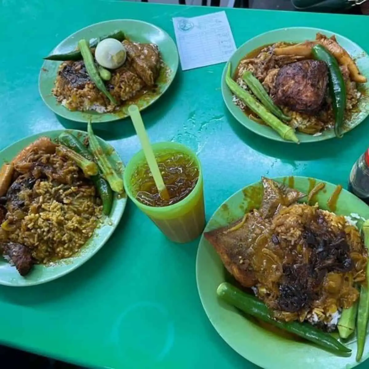  Four servings of Nasi Kandar from Kampung Melayu in a green plate and green table with one iced cold tea drink
