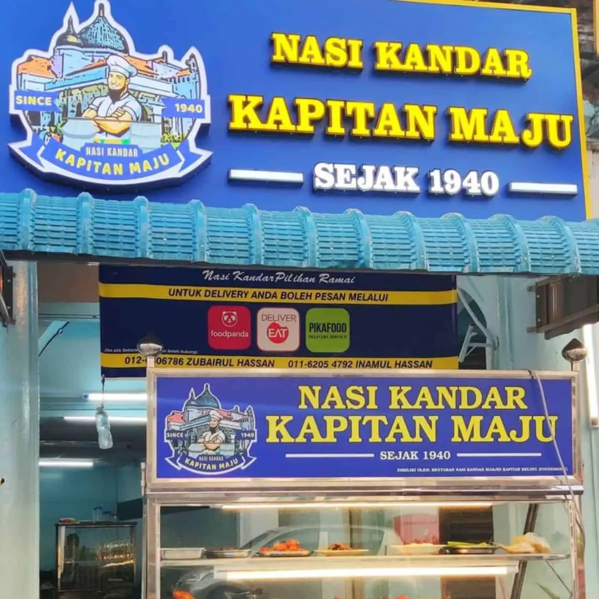  Front view of Kapitan Maju’s food house with blue and purple theme and food on display
