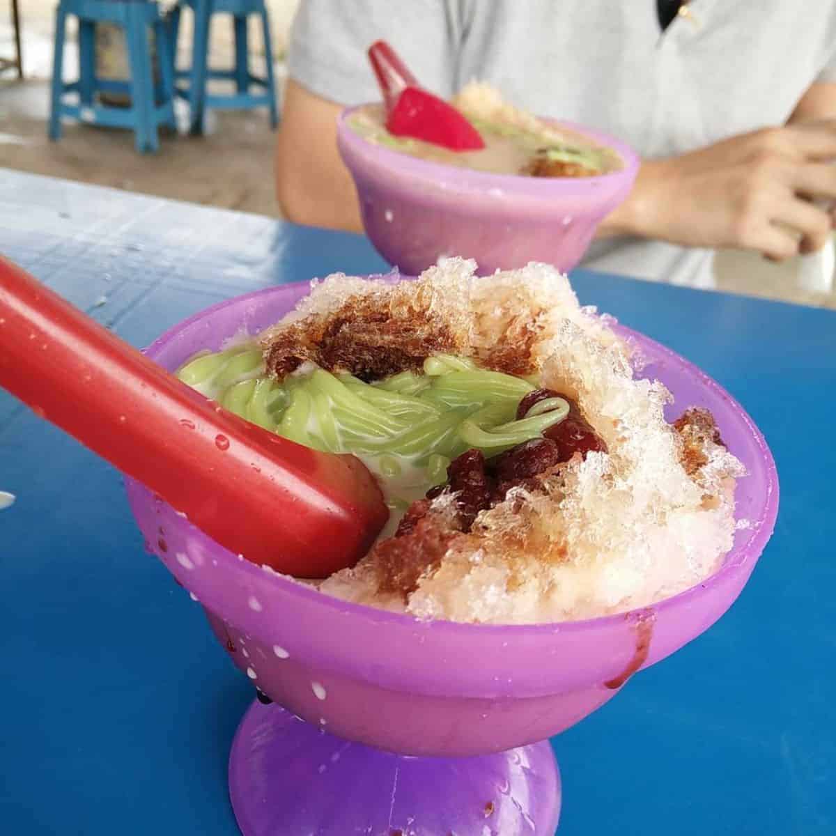 Two dessert bowl servings in purple plastic cups with red thick spoons