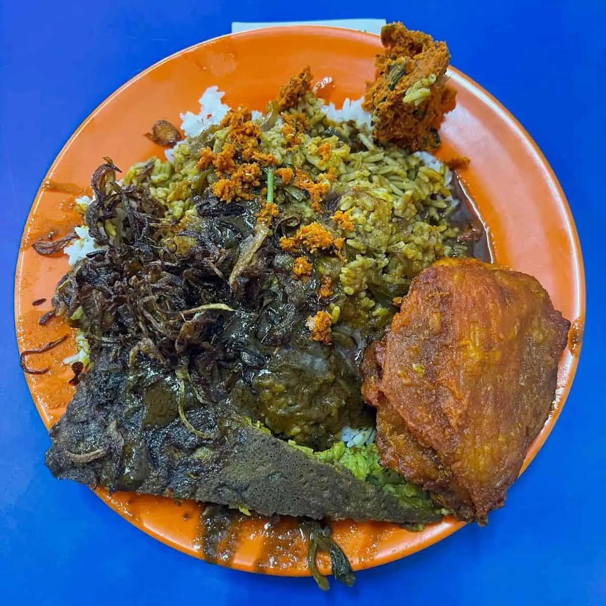 Black, orange and yellow hues of Nasi Kandar serving from Sulaiman in an orange plate