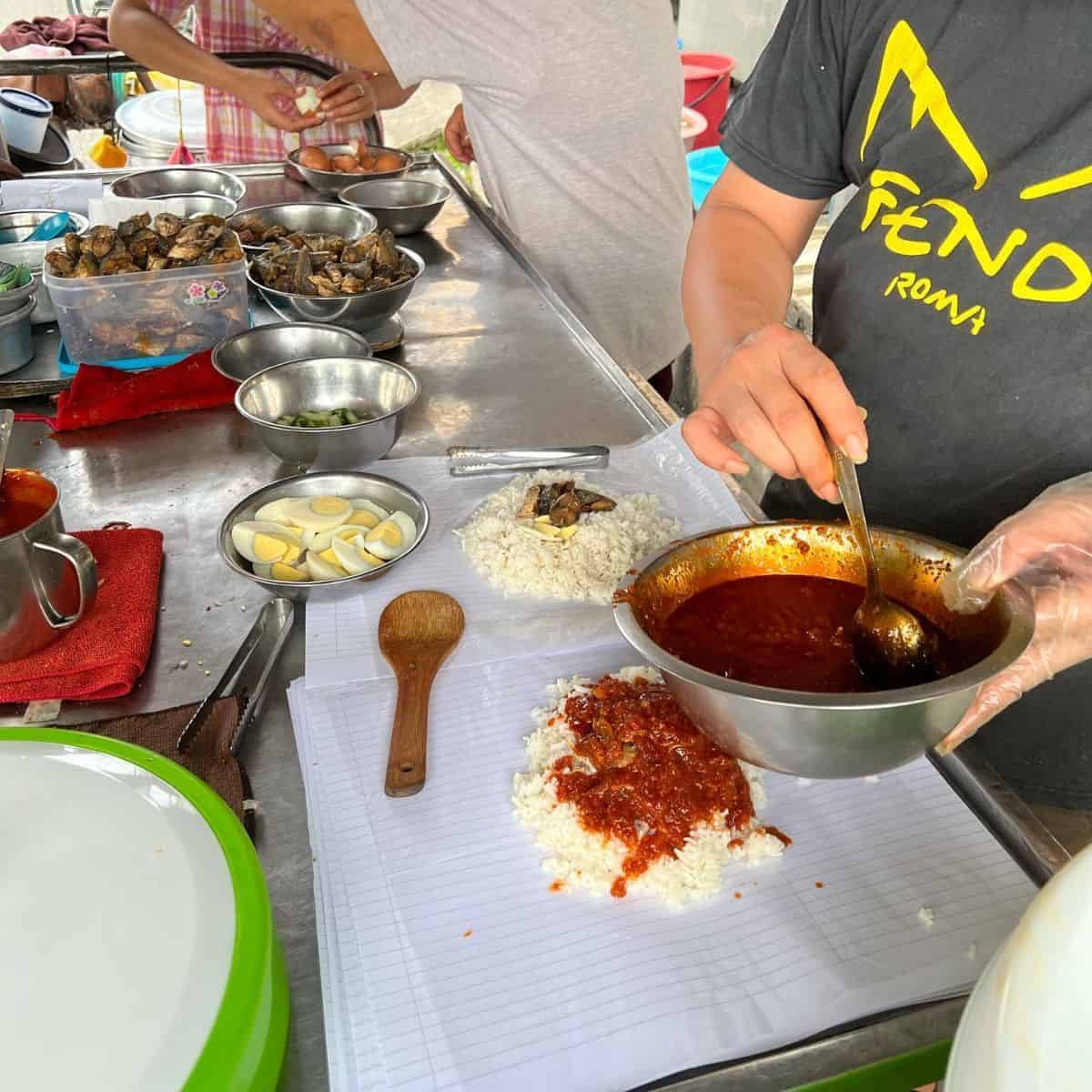 Paya Terubongs staff preparing the fatty rice dish with the ingredients laid over the table