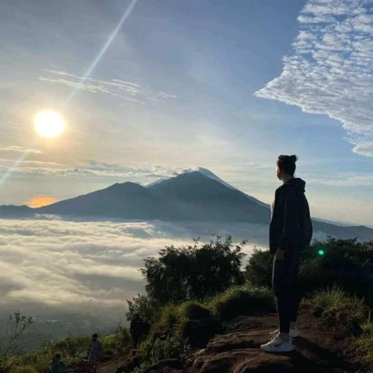 A lady enjoying the beautiful sunrise at Mount Batur above the sea of clouds