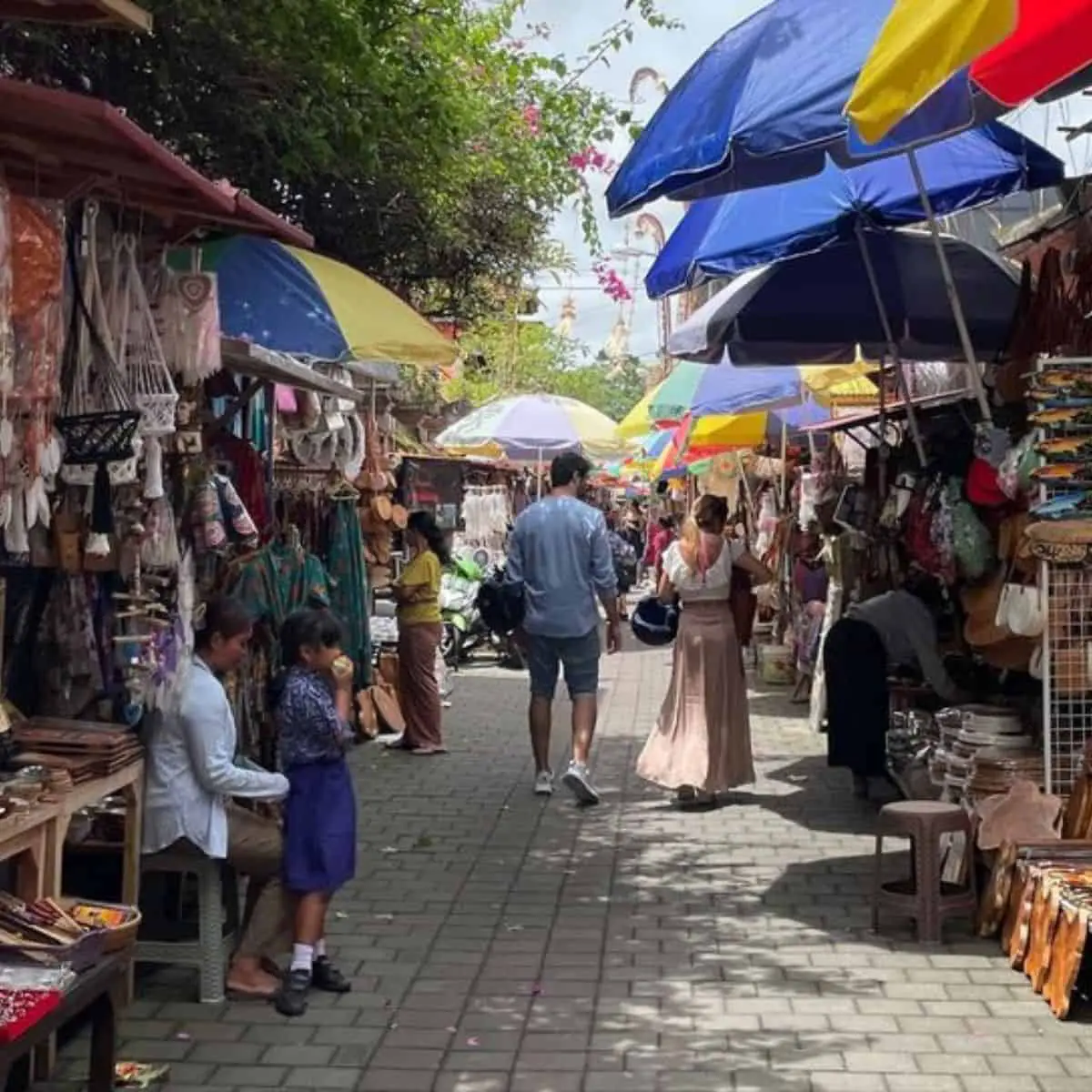 Stalls filled with handicrafts and souvenirs at Ubud Market with people strolling around