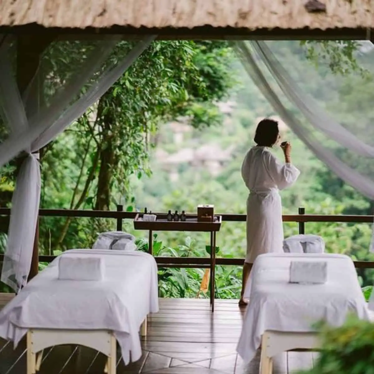 The open spa area of Alila with white curtains and sheets with a short-haired woman in white robe