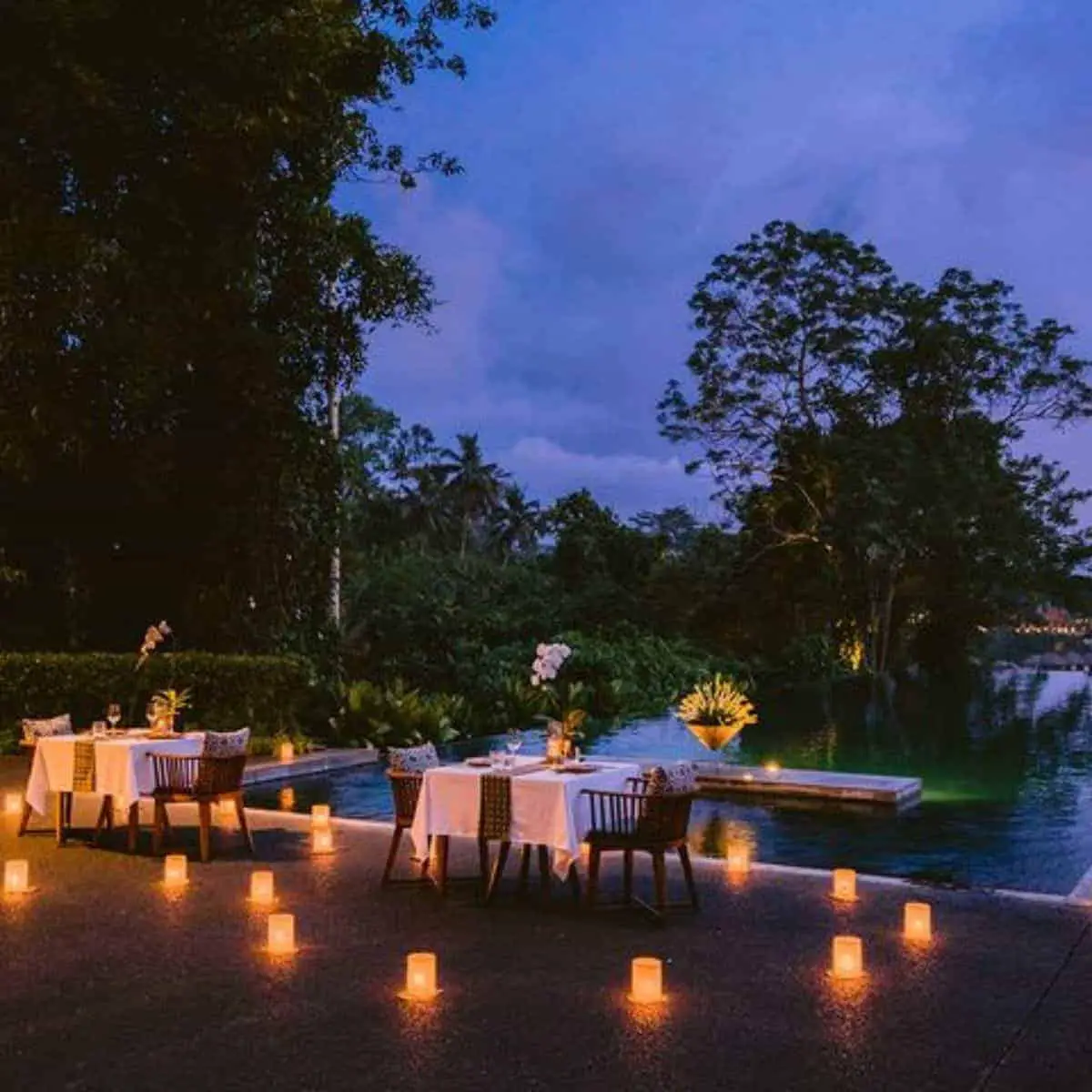 The romantic setting of two dining tables with candle lighting in the poolside of Alila