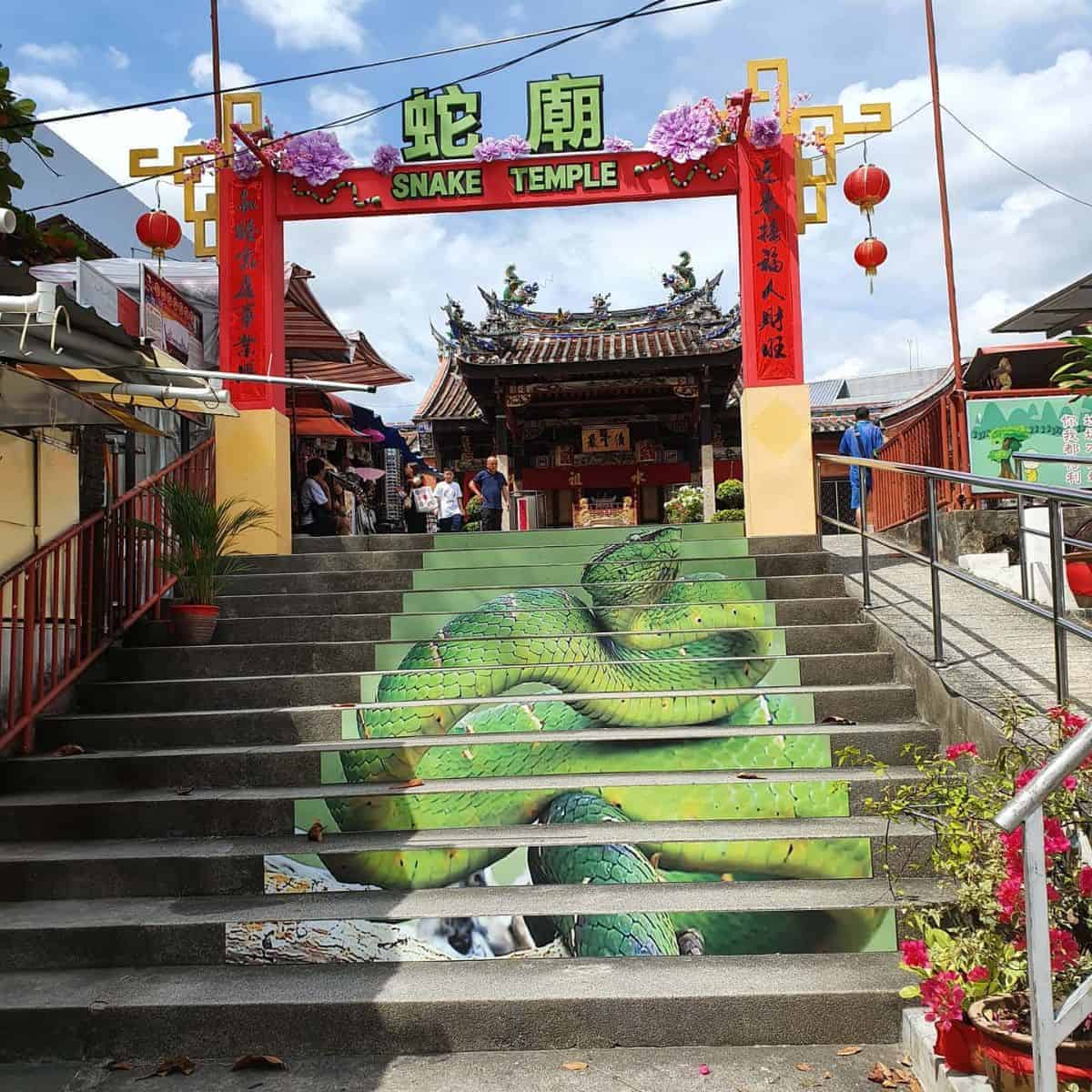 The entrance gate of the Snake Temple in Penang with green snake-painted staircase