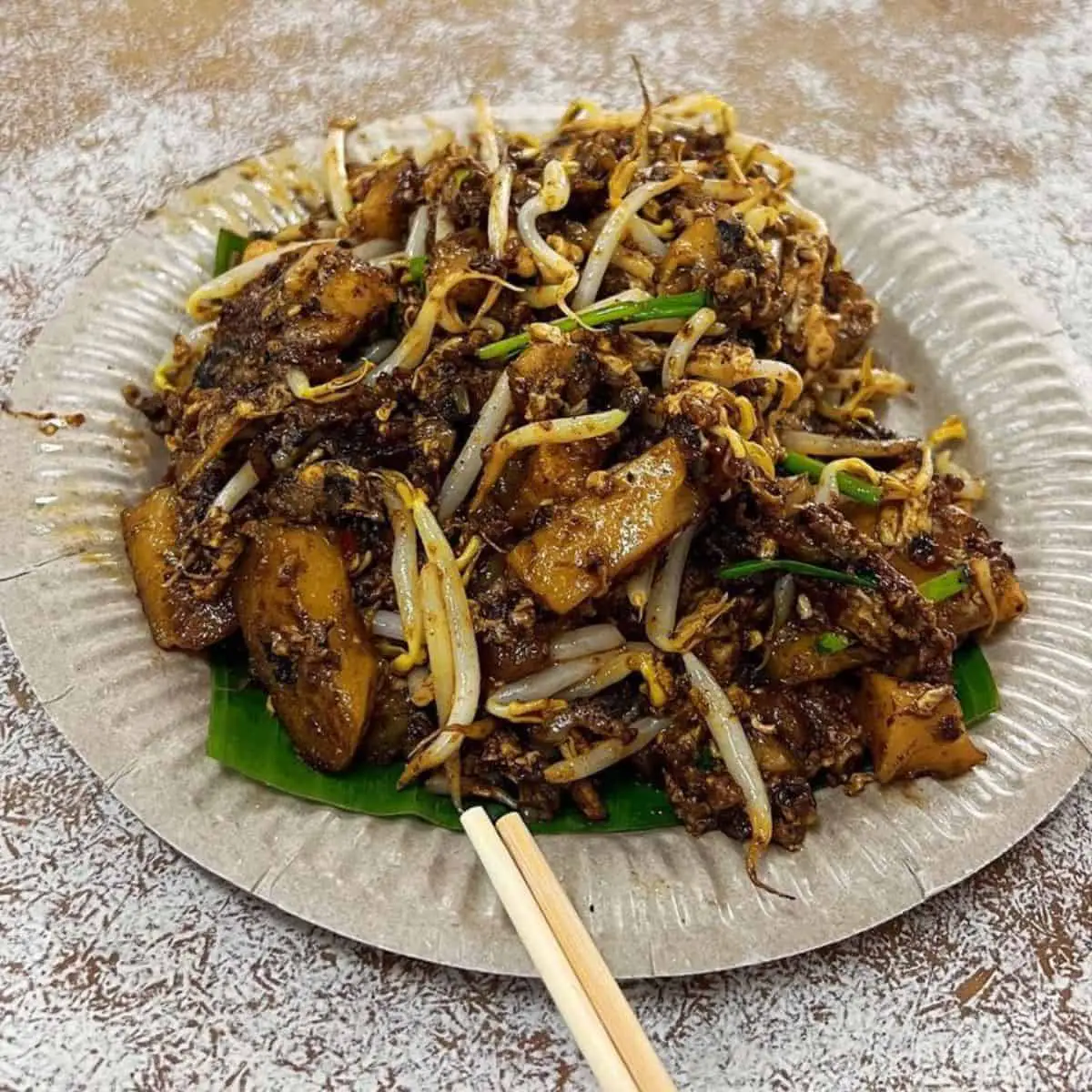 Sumptuous Penang street food in a paper plate and banana leaf underneath
