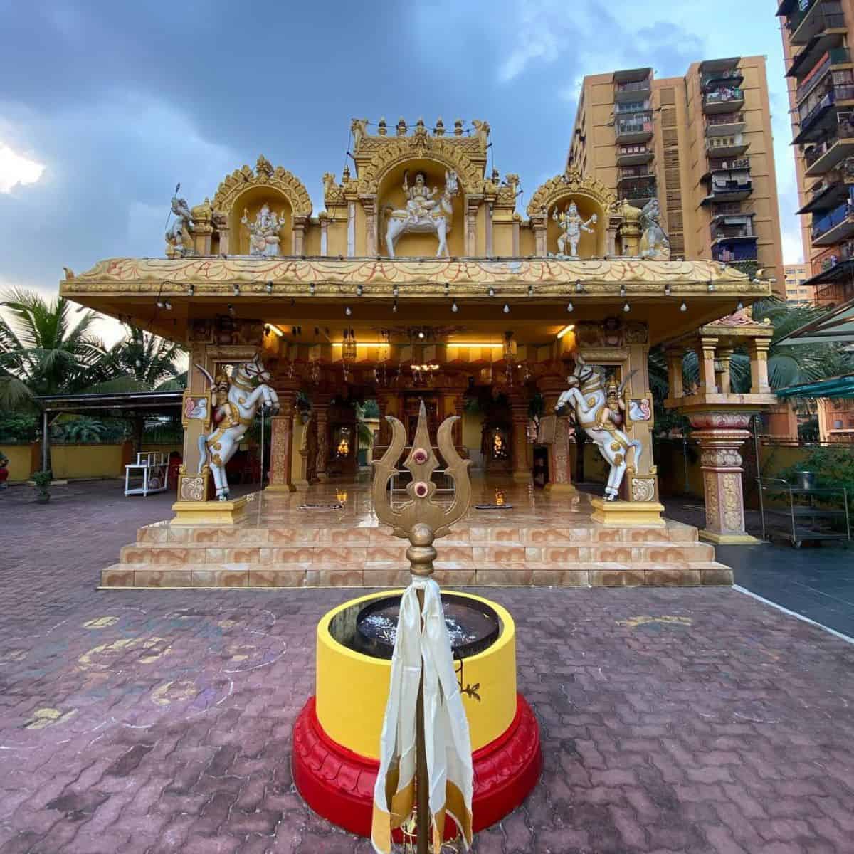 Sri Muniswarar in gold hue surrounded with tall buildings