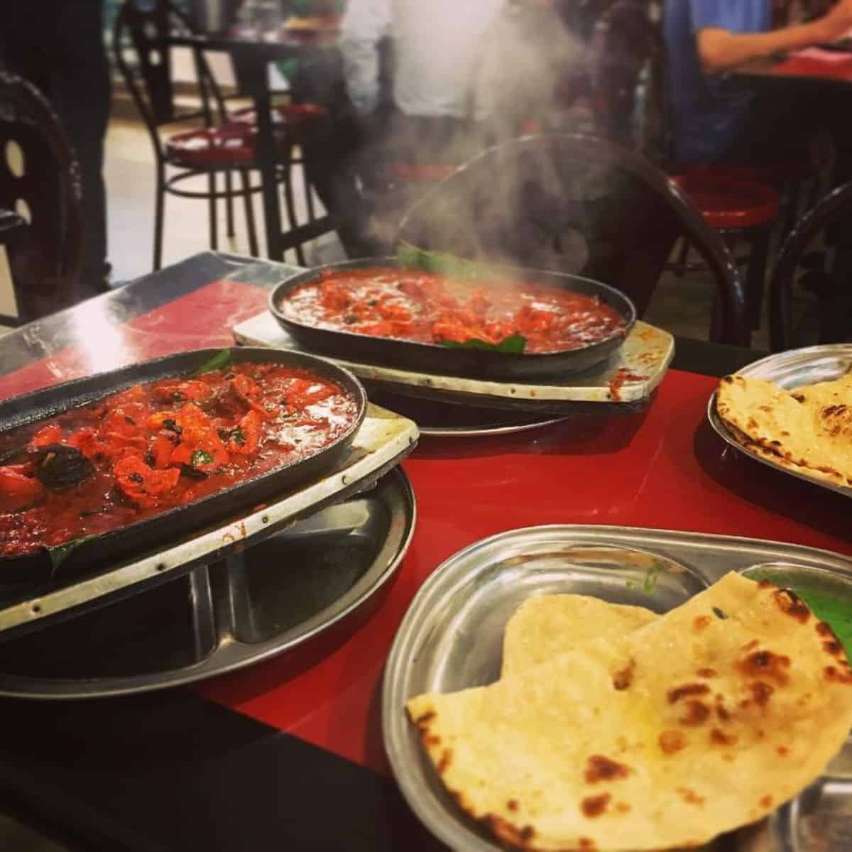 Two servings of sizzling Butter Chicken Masala paired with Pita bread