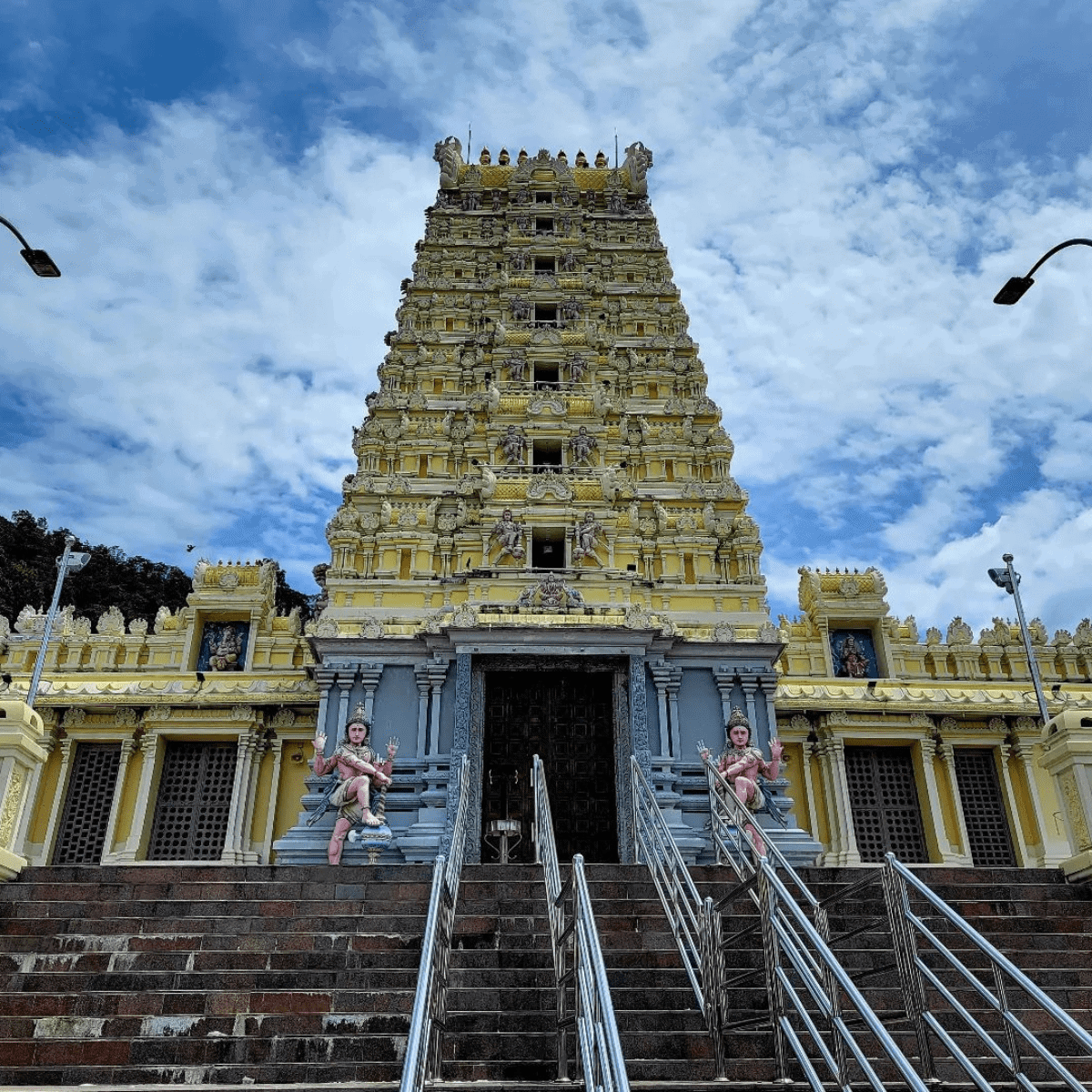 Towering facade of a building almost reaching the blue skies with two statues in the entrance door.