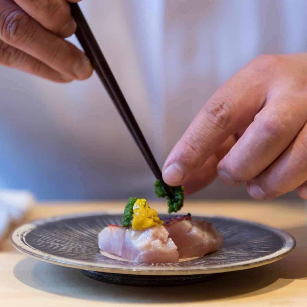 A chef preparing sushi using fresh cuts of fish meat from Niseko