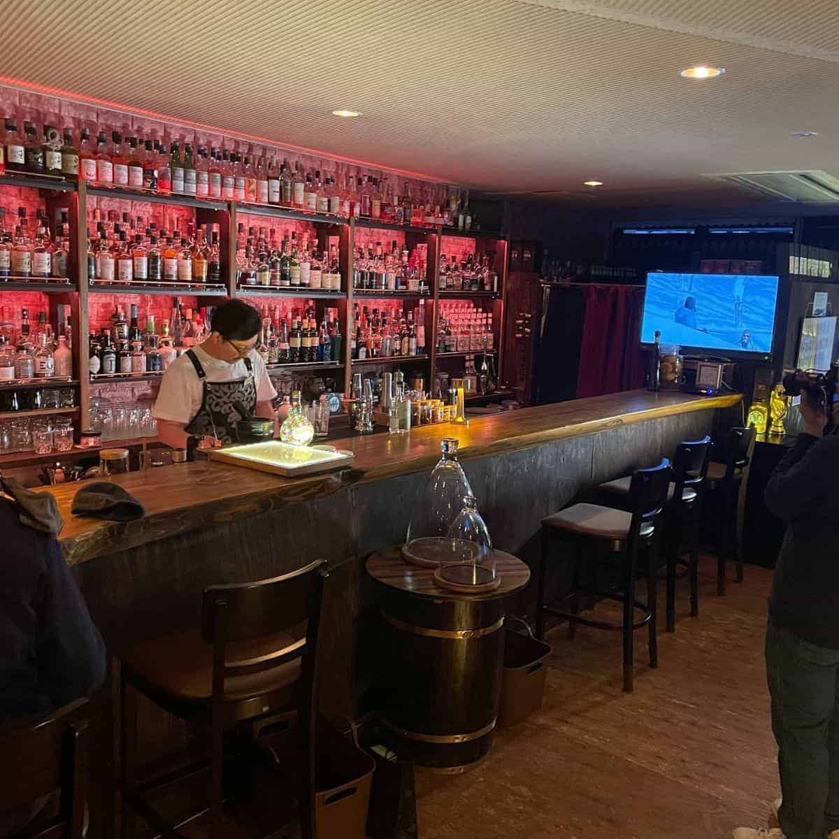 The owner of Toshiro Bar in Niseko with drinking bottles on display